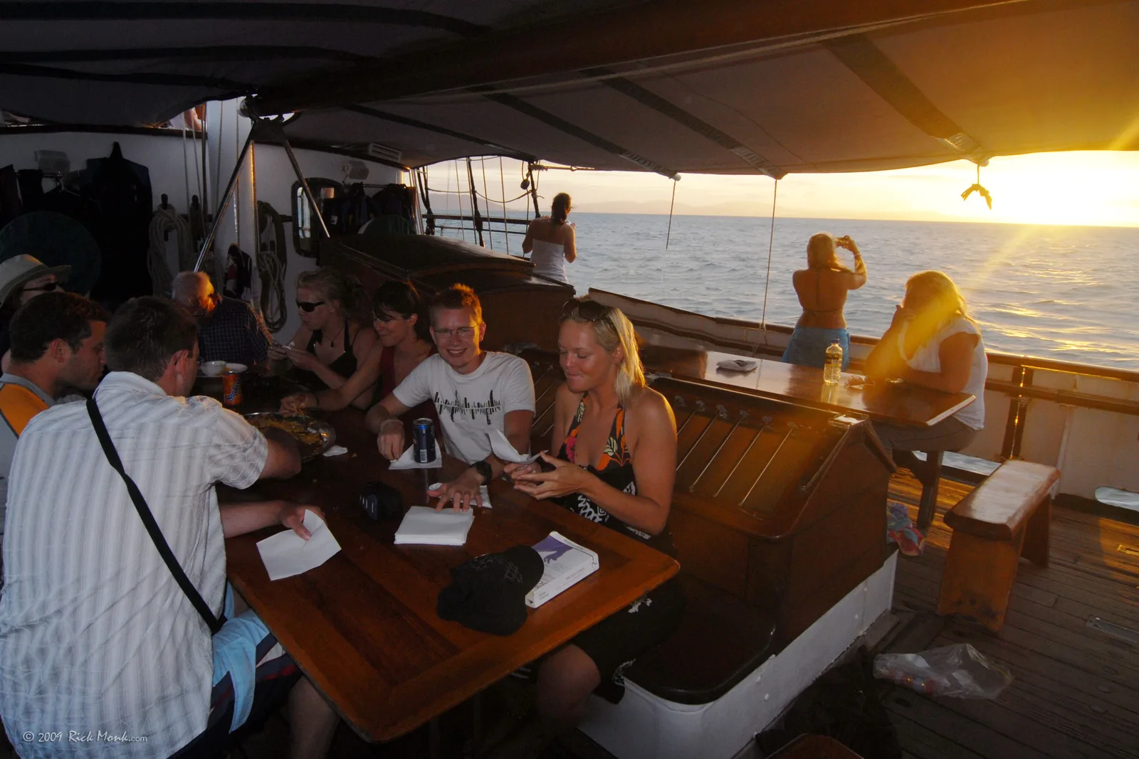 Guests sharing dinner on deck of Solway Lass at sunset