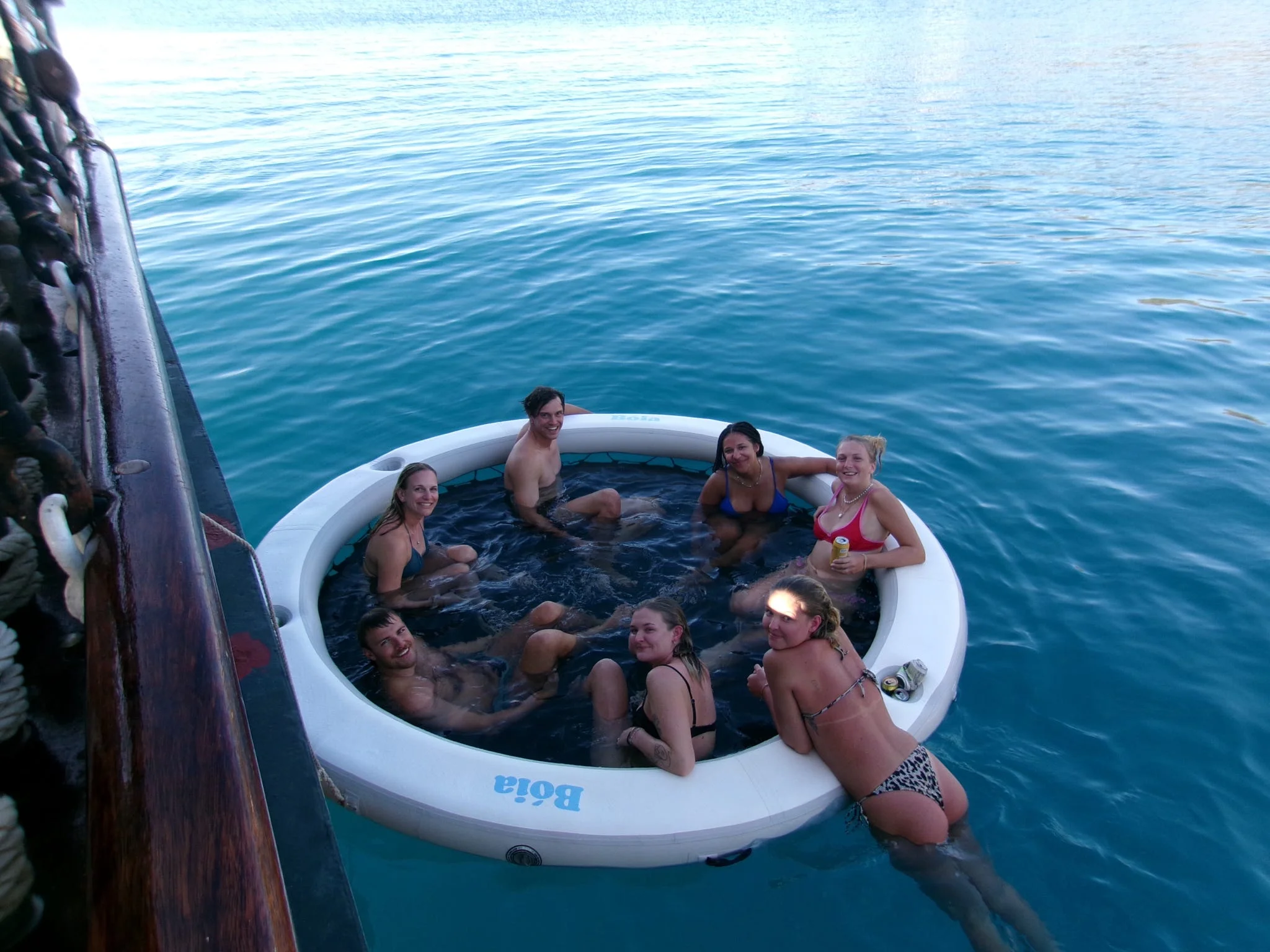 Guests relaxing in the floating sea pool beside the ship