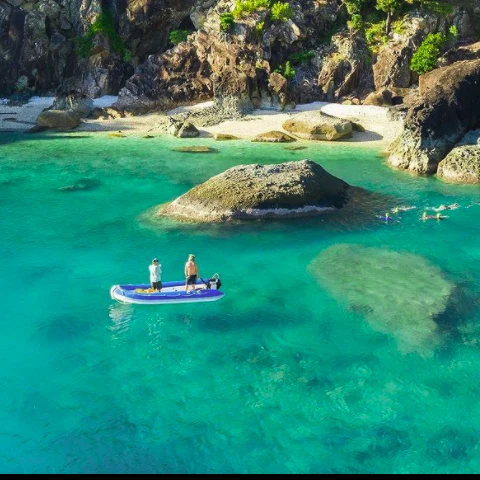 Guests paddleboarding and snorkelling in a secluded turquoise cove